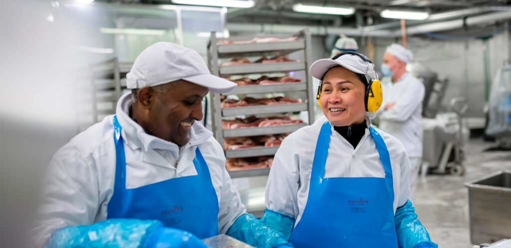 Bild på två arbetare som jobbar med att paketera kött.